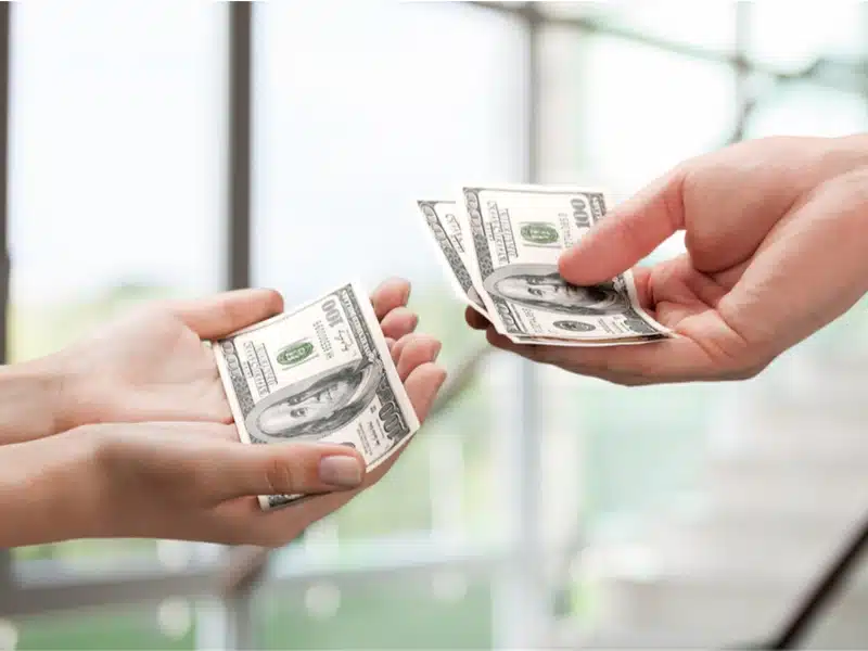Hands exchanging money for debt settlement fees