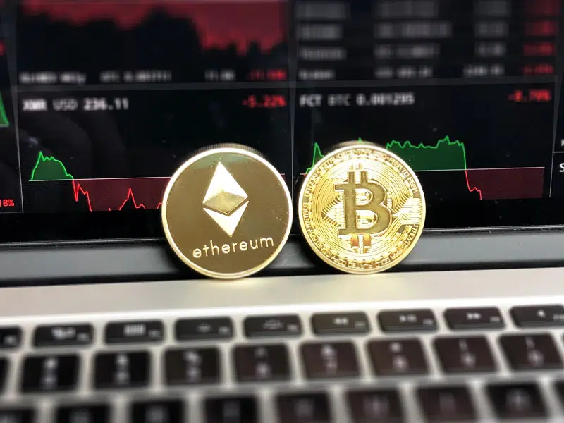 This is an Ethereum coin and bitcoin in front of a crypto trading platform.